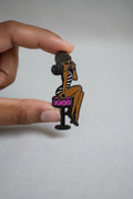 Pin of a woman sitting on a stool with a pink seat held by a hand against a gray background